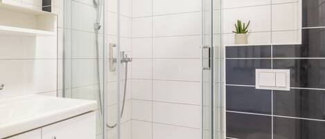A modern bathroom with a glass-enclosed shower, a white toilet, and a white sink with a cabinet.