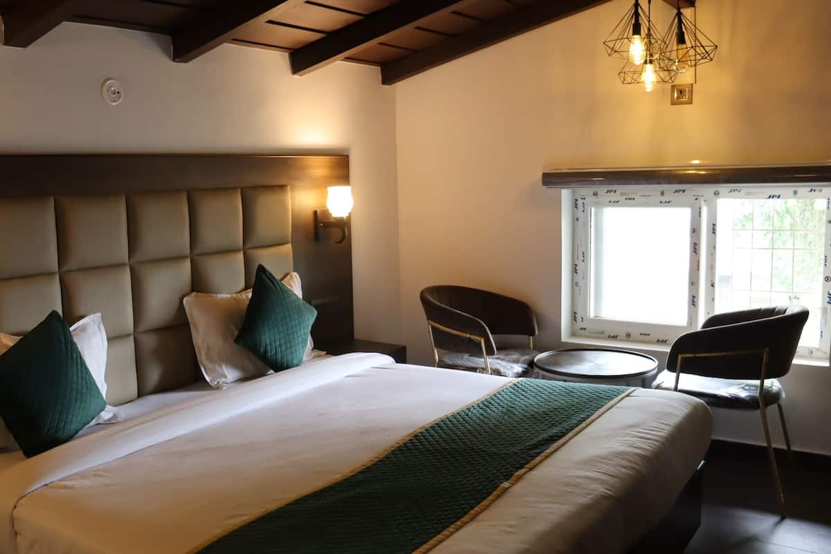 Une chambre d’hôtel avec un grand lit, une tête de lit dotée d’un éclairage intégré, une petite table ronde et une chaise.
