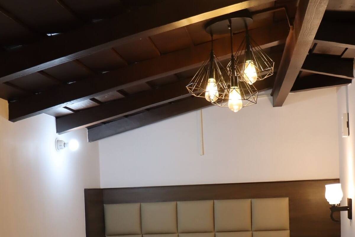 Une chambre d’hôtel avec un lit, une tête de lit et un luminaire au plafond.