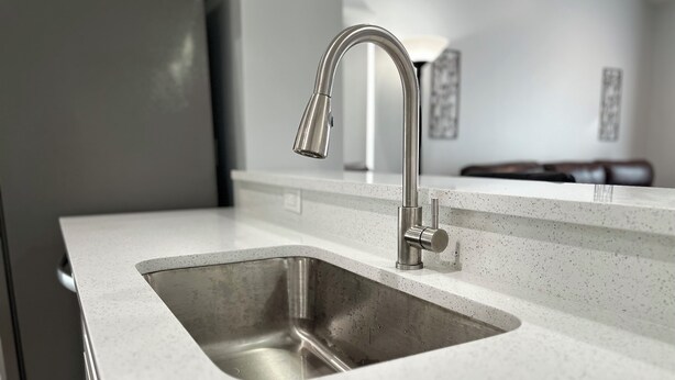 A modern kitchen with a stainless steel sink and faucet.