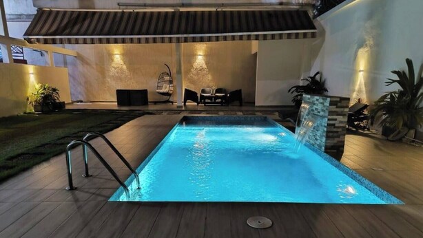 A rectangular swimming pool with a metal ladder on one side, surrounded by a wooden deck.