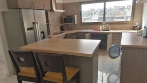 A compact kitchen with a dining area, a built-in oven, a microwave, and a large window offering a city view.