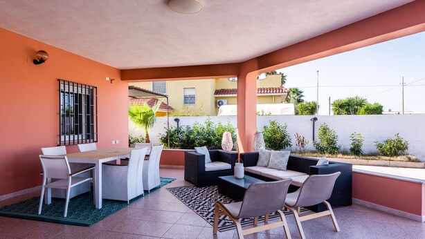 A covered outdoor patio with a dining table and chairs, a sofa, and a coffee table.