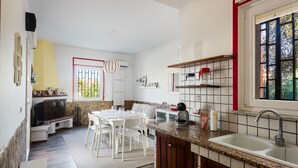 A kitchen with a dining area, a built-in oven, and a window with a view of greenery.