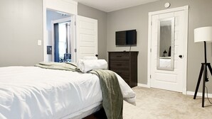 Un dormitorio con cama, cómoda, televisor y lámpara.
