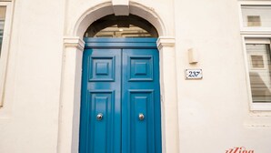 Una puerta azul con una placa de número '237' en un edificio blanco.