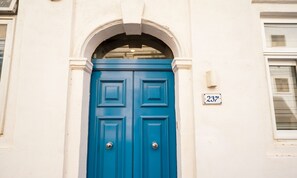 A blue door with a number plate '237' on a white building.