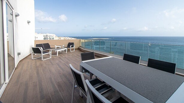 Un balcon avec vue sur la mer, une table et des chaises.
