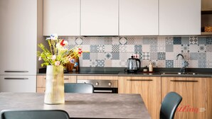 Une cuisine moderne avec des meubles blancs, un pare-feu en carreaux et un coin repas comprenant une table et des chaises.