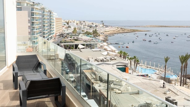 Un balcon avec vue sur une plage et un port de plaisance.