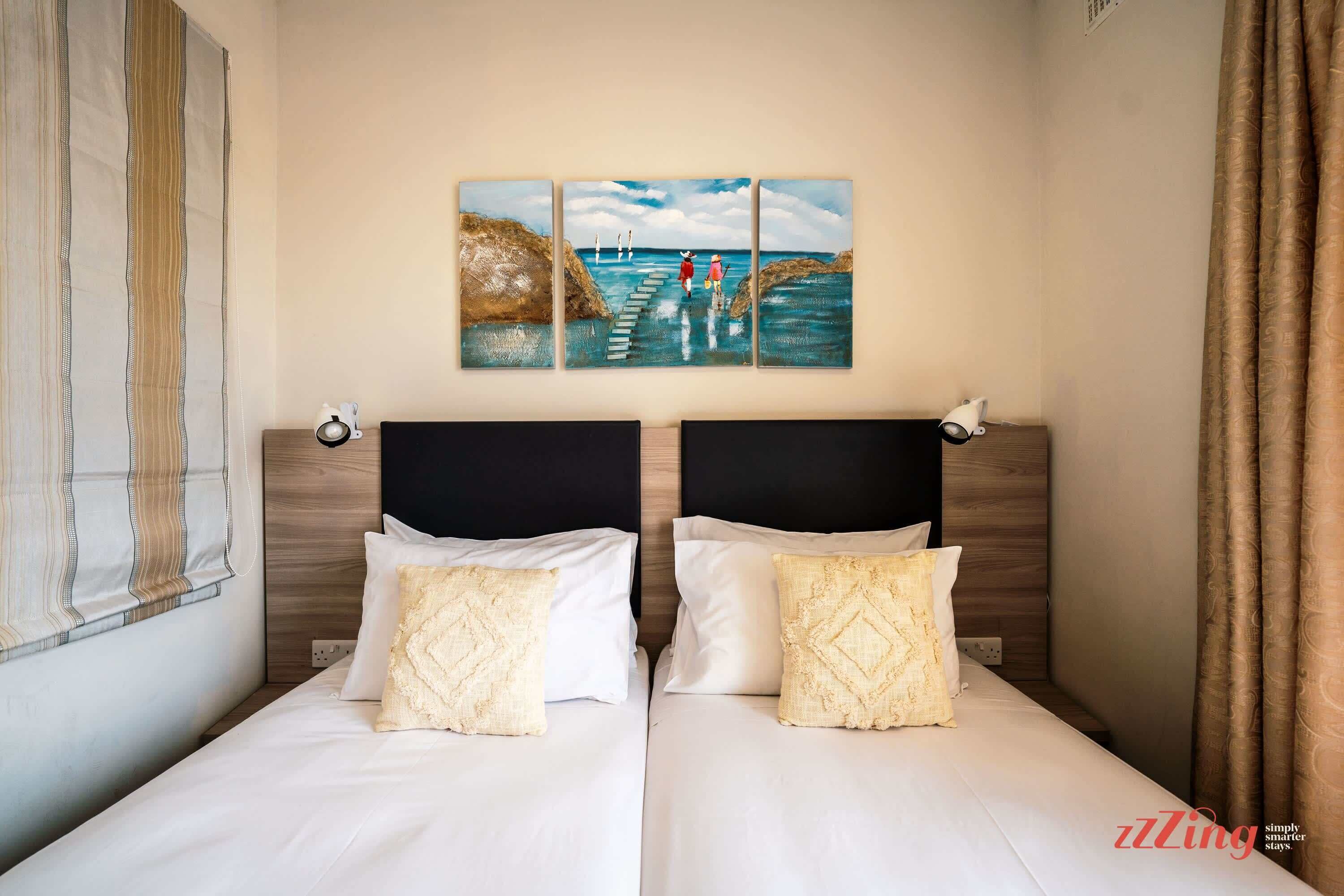 A double bed with a headboard, two pillows, and a painting above it.