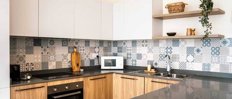 A modern kitchen with white cabinets, a black countertop, and a patterned backsplash.