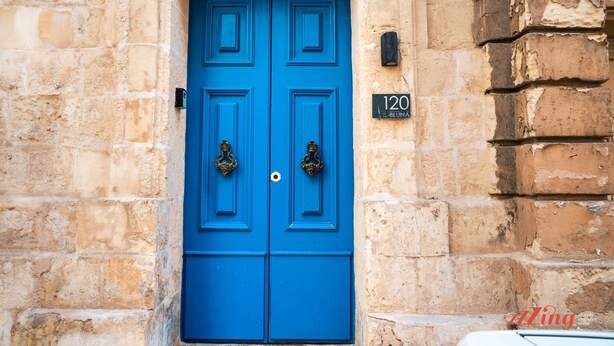 Une porte bleue avec une plaque portant le numéro « 120 » et un petit panneau placé au-dessus.