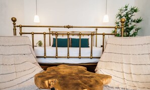 Une chambre à coucher avec un lit, des tables de chevet et une plante suspendue.