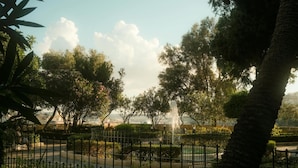 Un parque con una fuente, árboles y una cerca.