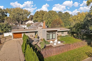A modern house with a garage, patio with outdoor furniture, and a well-maintained lawn. - "The Modern Muse" at Lake Harriet- by Roxy Rentals (Minneapolis)