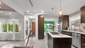 A modern kitchen with a central island, stainless steel appliances, and a view of the outdoors.