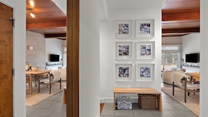 A modern interior with a dining area, a wall with framed pictures, and a wooden bench.