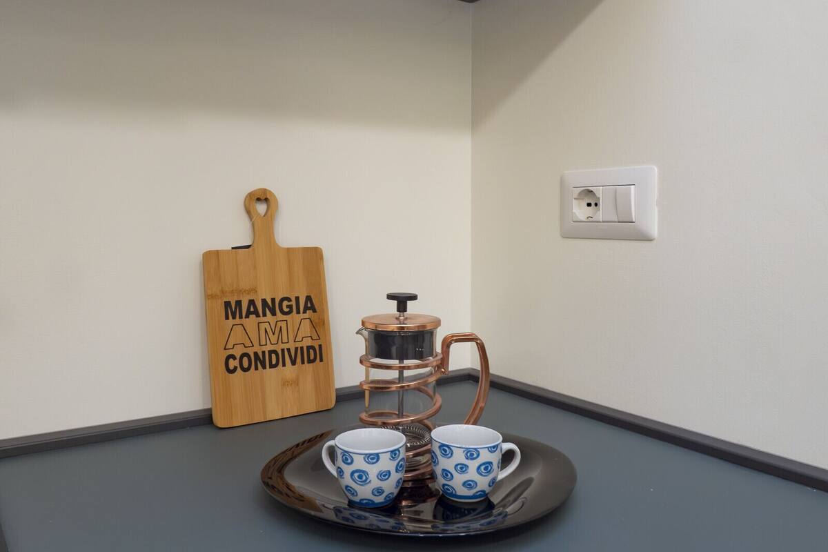 Un coin cuisine comprenant une planche à découper en bois, une machine à café et deux tasses posées sur un plateau.