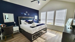 A bedroom with a bed, a desk, and a chair.