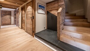 En trätrappa med svarta trappsteg som leder upp till en liten plattform, omgiven av träpanel och en inramad tavla på väggen.