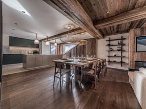 A modern kitchen with dark cabinets, a wooden dining table, and a large island.