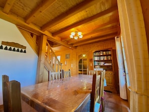 A wooden interior with a dining table, chairs, a staircase, a bookshelf, and a chandelier. - Apartment in chalet, Morillon, 3 bedrooms, parking, near center (Morillon Village)