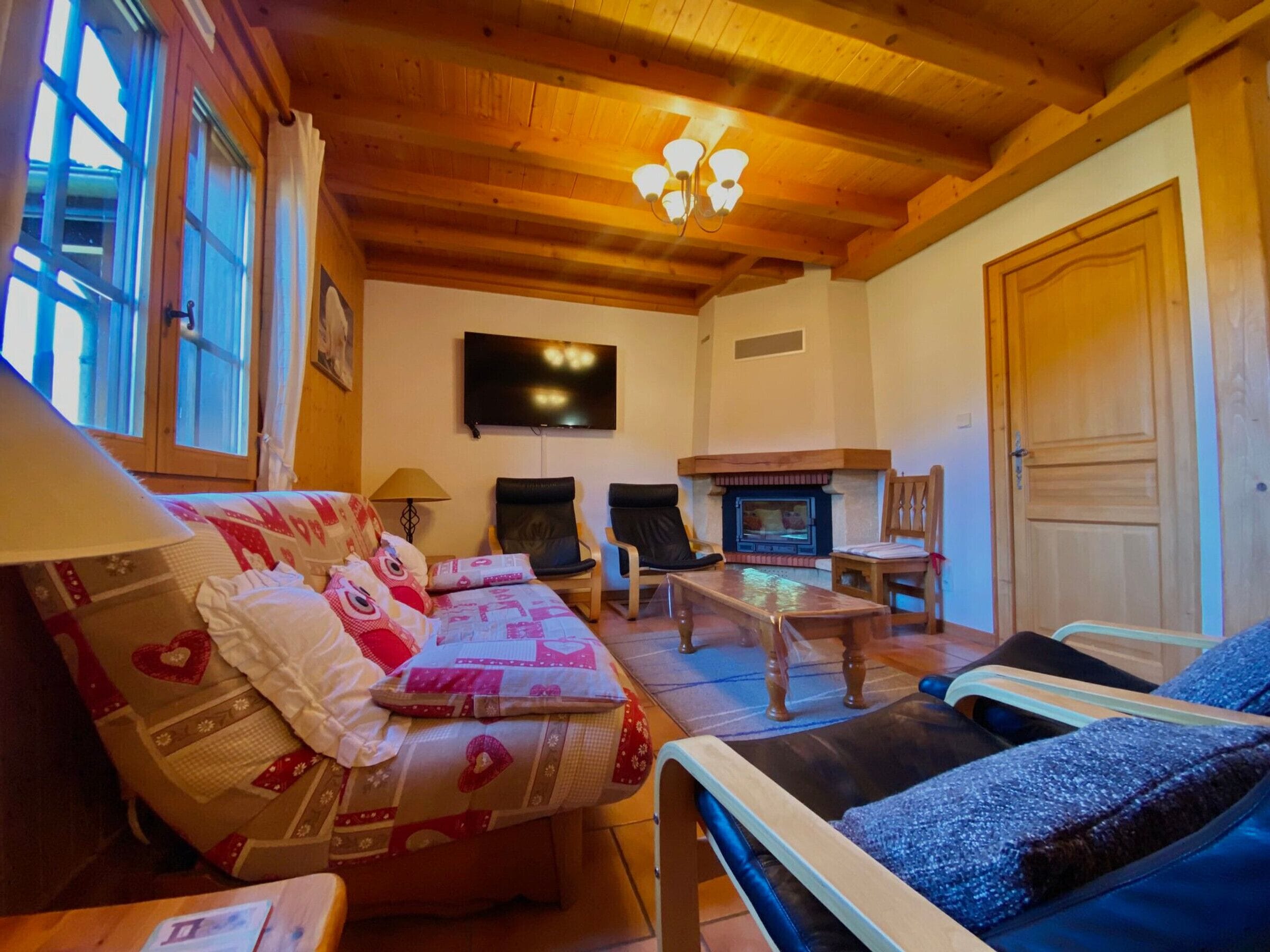 A cozy living room with a sofa, chairs, a fireplace, and a television.