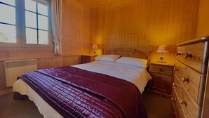 A wooden room with a bed, two bedside tables, a dresser, and a window with curtains. - Cozy duplex for 6 in Morillon with parking (Morillon Village)