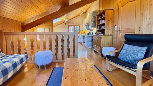 A cozy cabin interior with a wooden ceiling, a dining table, a sofa, and a kitchen area. - Cozy duplex for 6 in Morillon with parking (Morillon Village)
