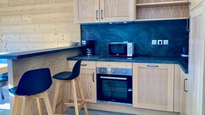 A modern kitchen with wooden cabinets, a black countertop, a microwave, a coffee maker, and a built-in oven.
