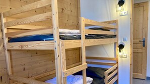 A bunk bed room with a wooden floor and a door.