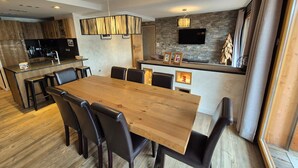 Eine moderne Küche mit einer zentralen Kochinsel, einem Essbereich mit Holztisch und -stühlen sowie einer Wand mit Steinverkleidung.
