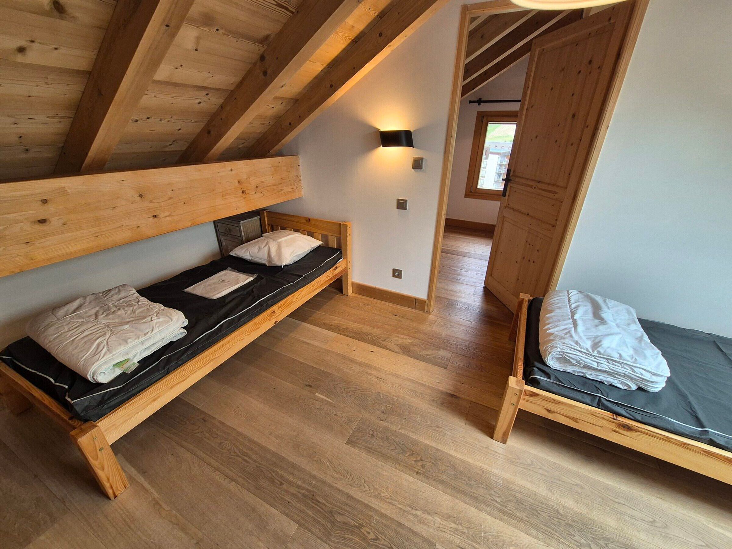A room with two wooden bunk beds, a small cabinet, and a wall-mounted light fixture.