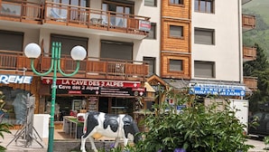 A multi-story building with wooden balconies and a sign for "La Cave des 2 Alpes". - Spacious duplex for 10 ppl. 250m from slopes - Pets allowed (Les Deux Alpes)