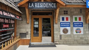 A building with a sign reading "LA RESIDENCE" and two signs indicating "MONITEURS (DIPLOMES DE L'ETAT)" and "MAESTRI ITALIANI". - Spacious duplex for 10 ppl. 250m from slopes - Pets allowed (Les Deux Alpes)