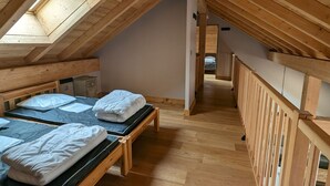 A cozy attic bedroom with two wooden beds, a skylight, and a wooden railing. - Spacious duplex for 10 ppl. 250m from slopes - Pets allowed (Les Deux Alpes)