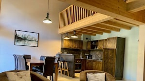 A cozy living room with a dining area, wooden ceiling beams, and a kitchen with wooden cabinets. - Spacious duplex for 10 ppl. 250m from slopes - Pets allowed (Les Deux Alpes)