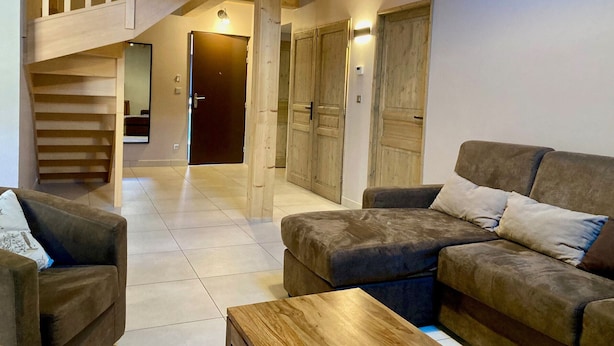 A spacious living area with a wooden staircase, a sofa set, and a wooden coffee table. - Spacious duplex for 10 ppl. 250m from slopes - Pets allowed (Les Deux Alpes)