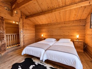 A wooden cabin bedroom with two beds, nightstands, and a cowhide rug.