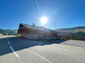 A rustic wooden building with a stone foundation, a metal roof, and a clear sky in the background.