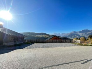 Entorno rural con camino de grava, cerca de madera y un granero.