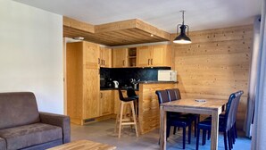 Un espacio habitable pequeño con kitchenette, mesa de comedor de madera y sofá.