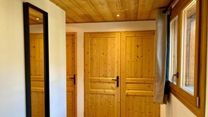 Un pasillo con puertas dobles de madera y un espejo a la izquierda.