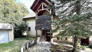 A rustic wooden house with a stone pathway leading to a wooden door.