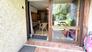 A wooden-framed door leading to a room with a bed, a chair, and a table.