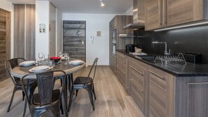 Una cocina moderna con armarios de madera, encimera negra y un área de comedor con una mesa redonda y sillas.