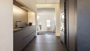 Een moderne keuken met een centraal eiland, ingebouwde apparatuur en uitzicht op de aangrenzende woonkamer.