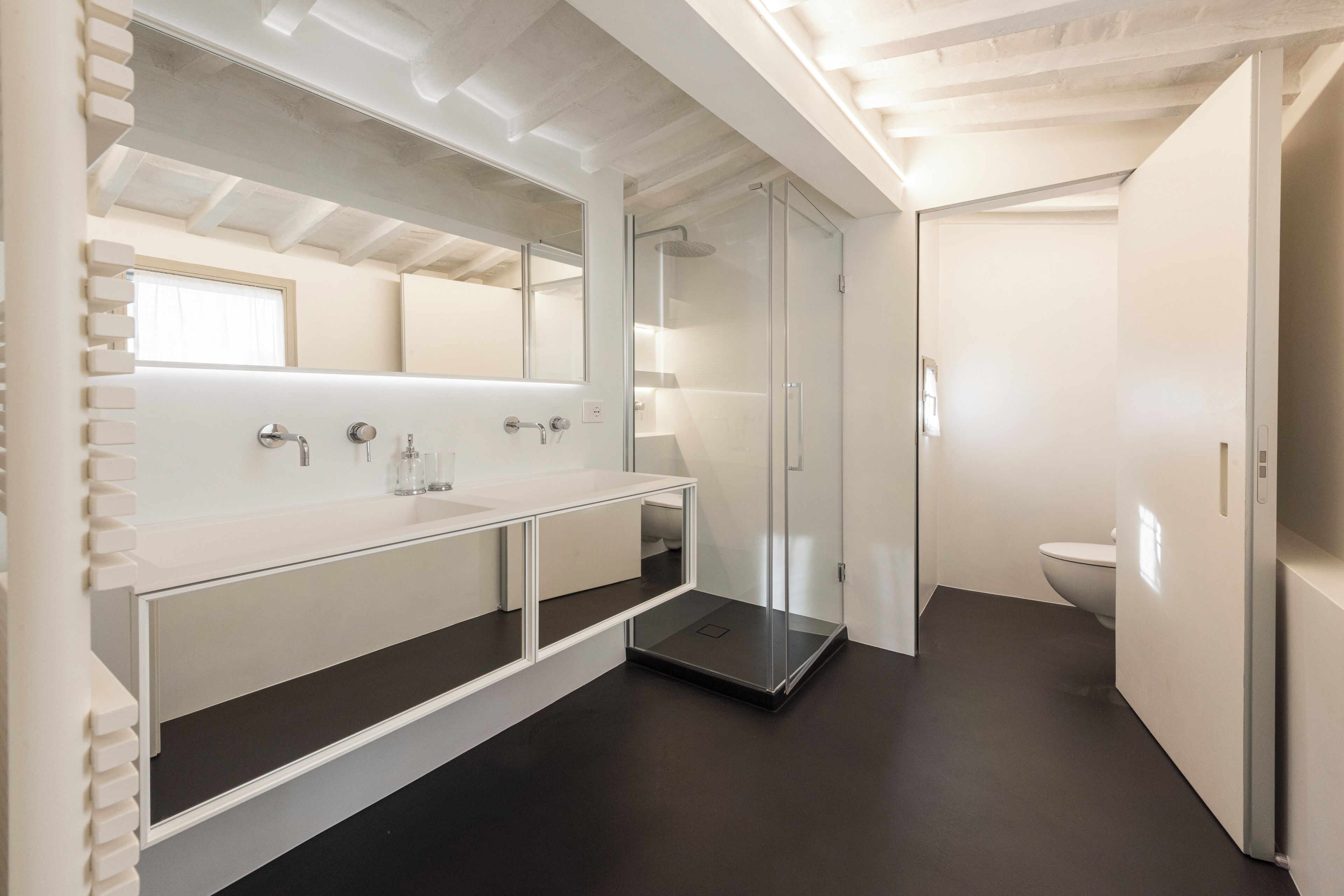 Une salle de bain moderne avec une douche à parois de verre, un lavabo blanc avec un miroir et des toilettes.