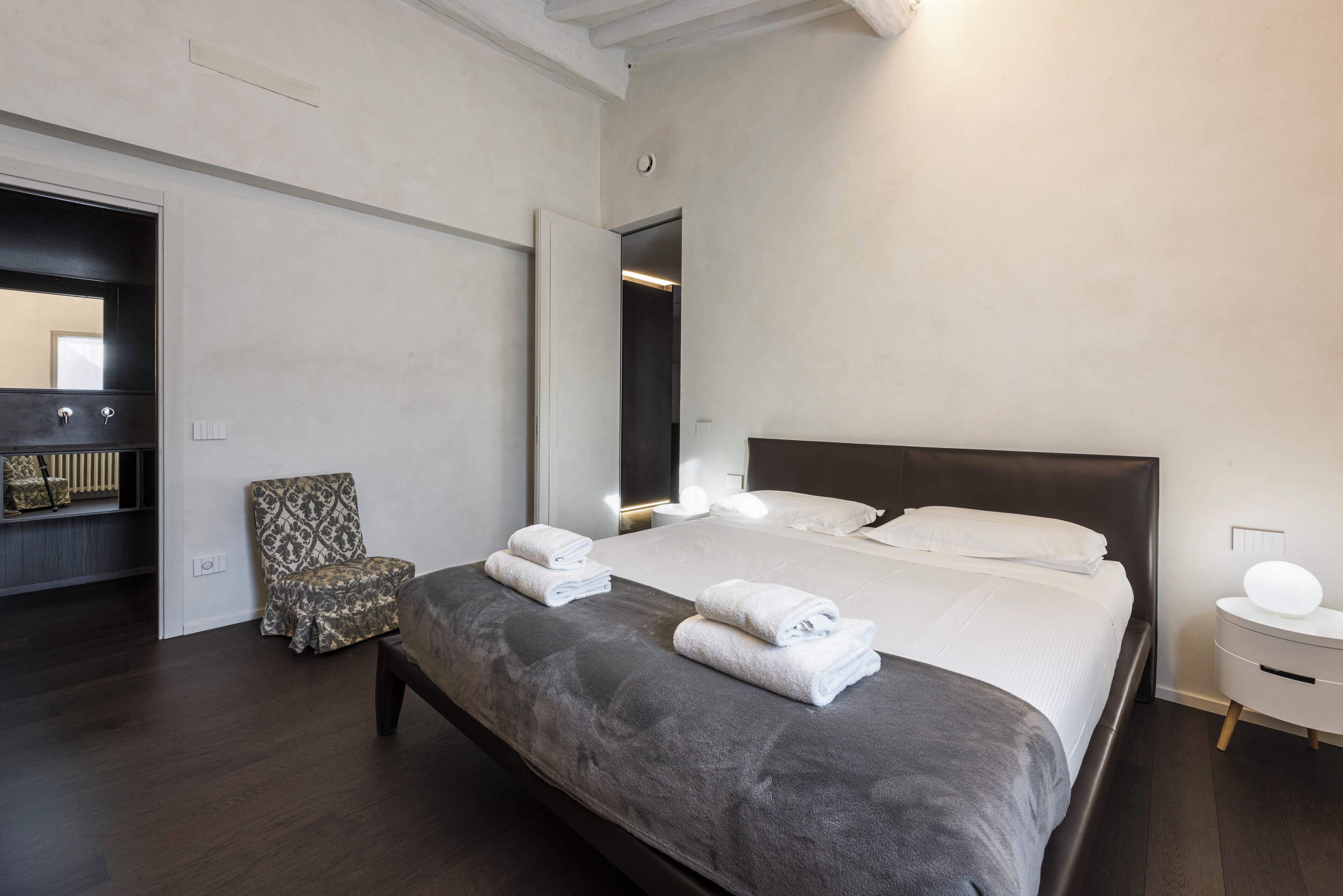 Une chambre à coucher moderne avec un grand lit, une chaise et une table de chevet.